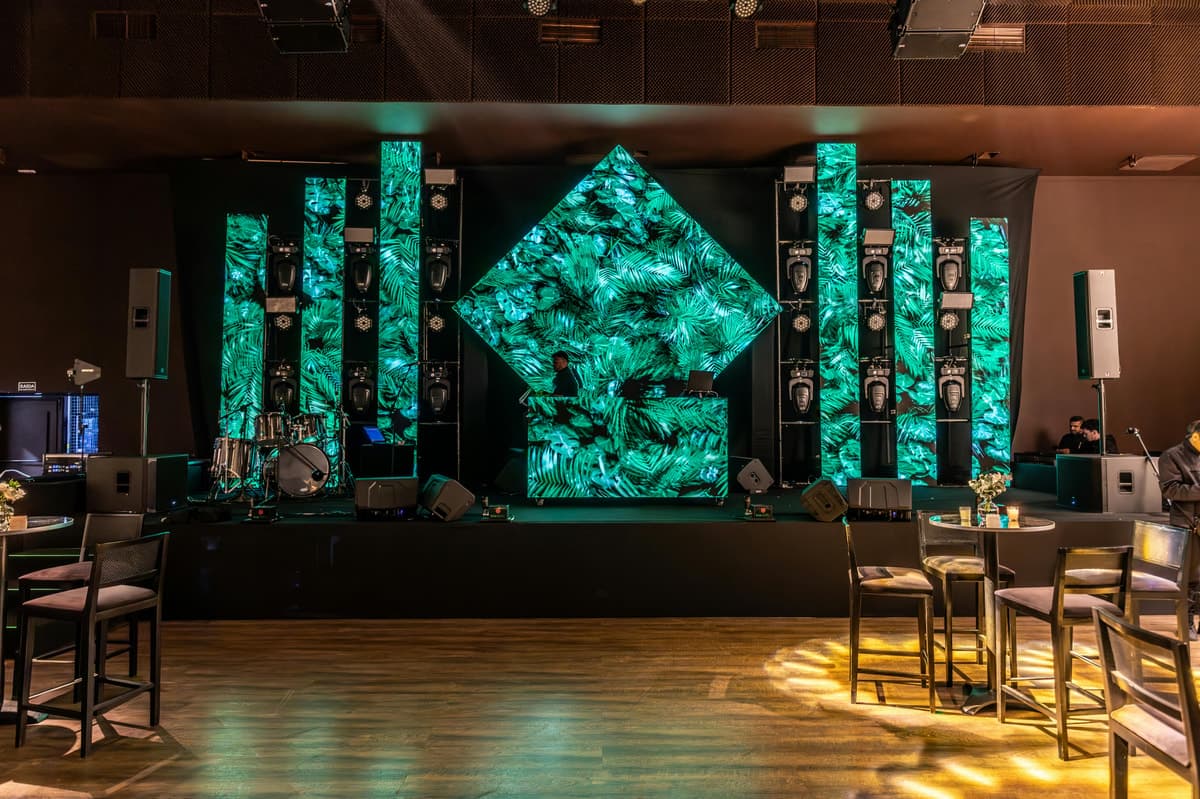 Scenă de eveniment cu panouri LED verzi și decor tropical